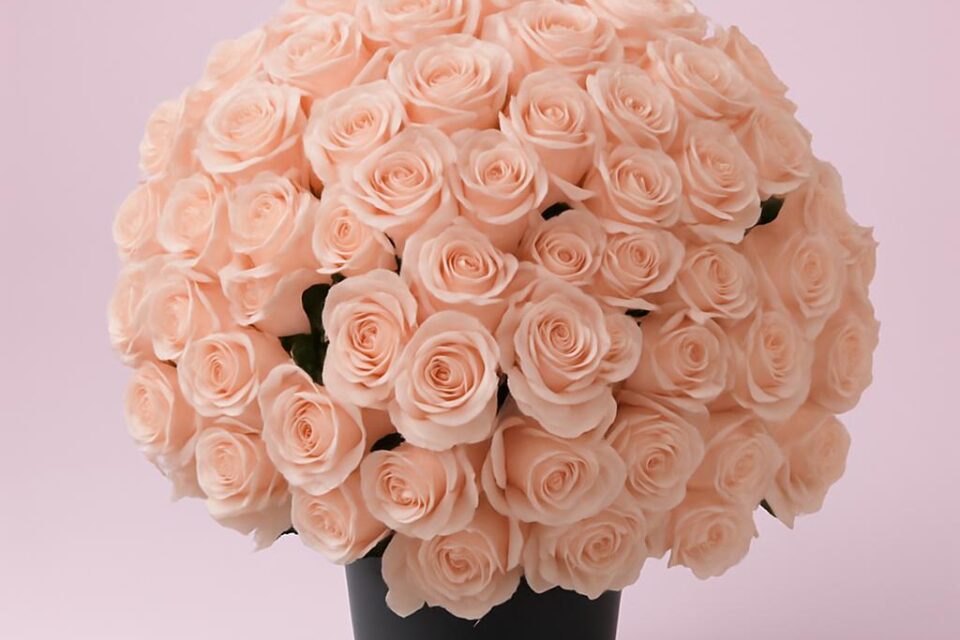 Großes rundes Arrangement aus zahlreichen hellrosa Rosenblüten in einer hohen dunklen Vase